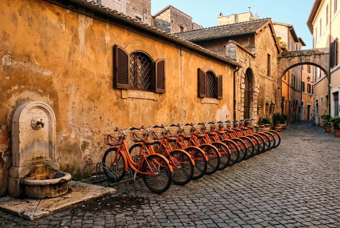 Row of orange rental city bikes lined up against an ochre wall in a Roman piazza